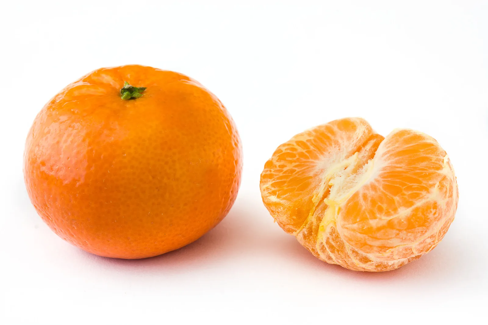 Mandarina fresca entera y pelada sobre fondo blanco